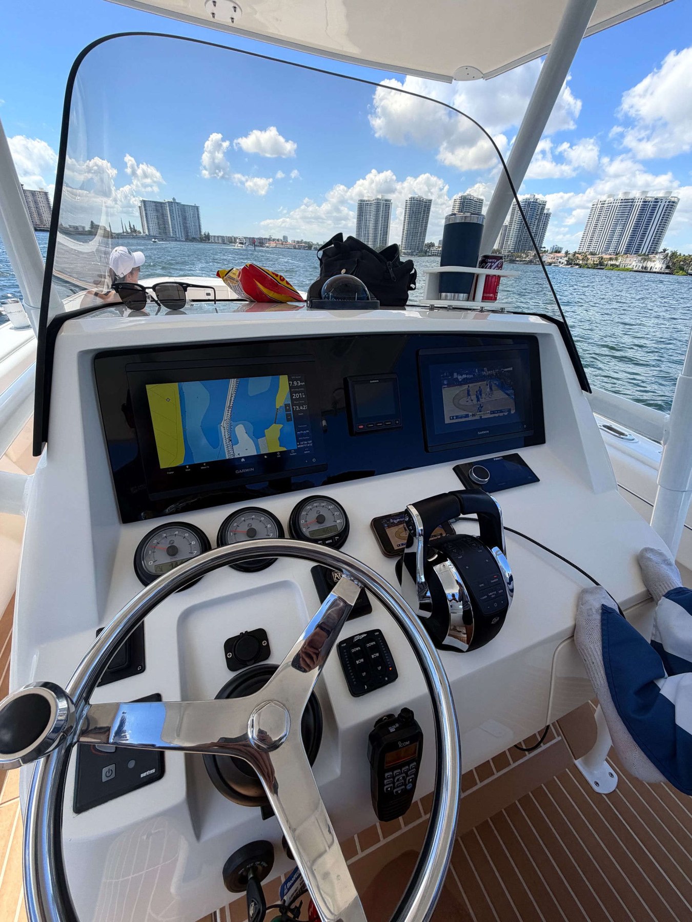 Blacked-out helm running the Intracoastal — triple Garmin with chartplotter, Miami skyline in background