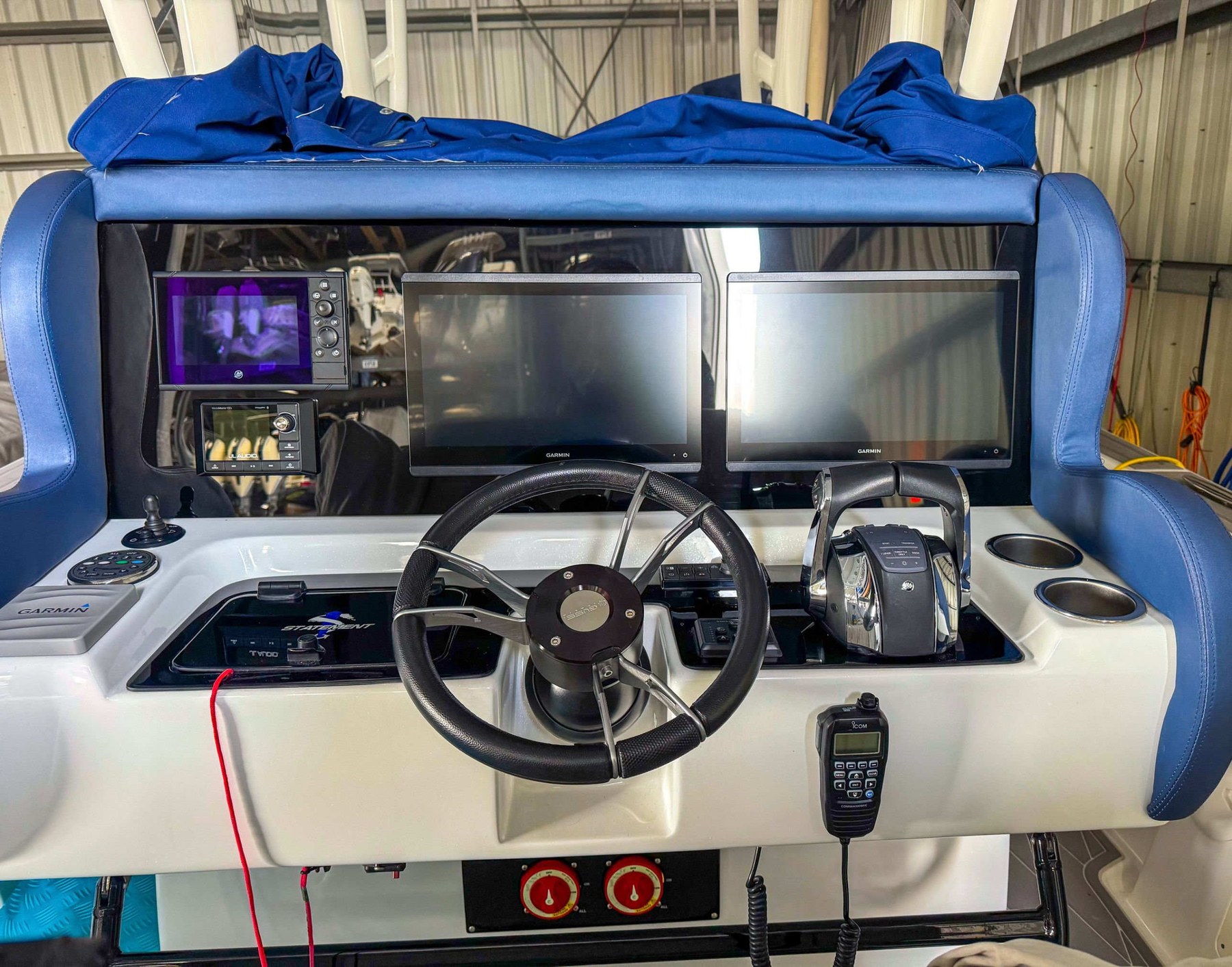 Dual Garmin displays with radar, sonar overlay, and integrated breaker panel on a blacked-out console